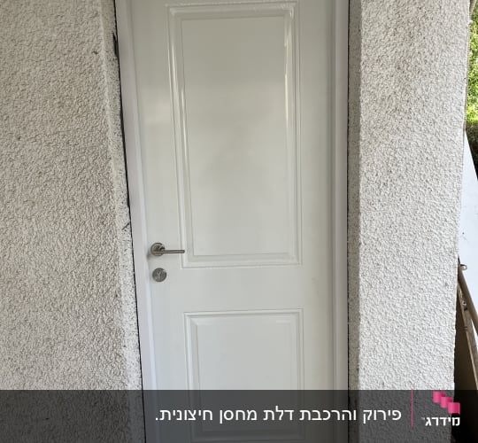 דלת לבנה עם ידית מתכת במסגרת קיר בטון